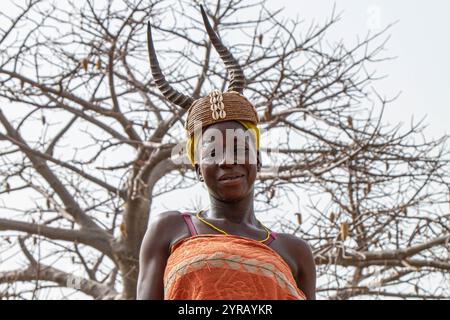 Femme en costume traditionnel avec chapeau corné souriant dans un village rural au Togo Banque D'Images