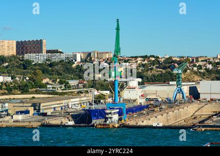 Marseille. France - 03 décembre 2024 : présente un chantier naval industriel avec deux grandes grues et un navire amarré, sur fond de résidences Banque D'Images