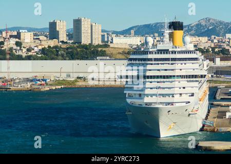 Marseille, France - 03 décembre 2024 : un port avec un bateau de croisière amarré, présentant l'infrastructure portuaire et une ville en toile de fond avec résidentiel et comme Banque D'Images