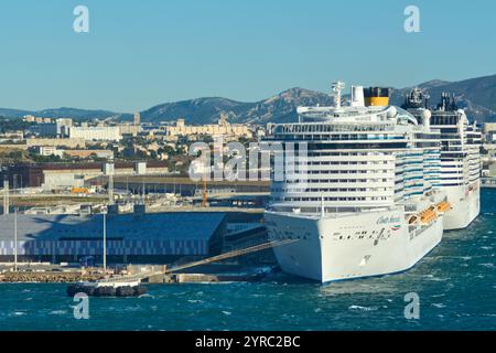 Marseille, France - 03 décembre 2024 : un grand bateau de croisière accoste au port, avec une ville et des montagnes en arrière-plan. L'image met en évidence les s. Banque D'Images