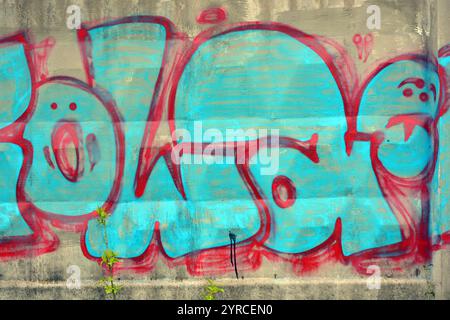A lettres bleues et grises et épaisses lignes rouges et cerises avec bordures rouges. Un graffiti représentant le mot KOWAH est sur une clôture en béton grise et brune. Banque D'Images
