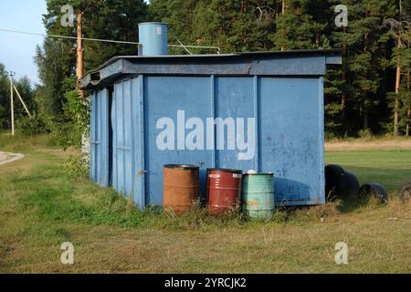 Moscou, Russie - 20 août 2024 : un hangar bleu avec trois tonneaux en face, situé dans la campagne pittoresque du village d'Ashitkovo Banque D'Images