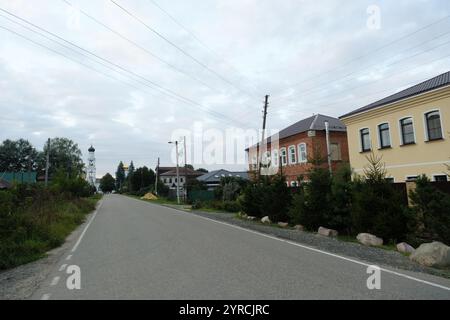 Moscou, Russie - 20 août 2024 : une rue paisible dans le village d'Ashitkovo, présentant l'architecture russe traditionnelle avec des arbres et le ciel ouvert Banque D'Images