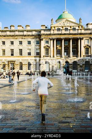 LONDRES, ANGLETERRE, Royaume-Uni - 3 MAI 2014 : garçon non identifié courant à travers les jets d'eau de la fontaine dansante dans la cour de Somerset House. Somerset H. Banque D'Images