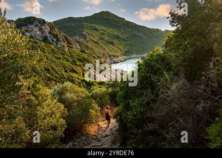 Belle femme descend un sentier au coucher du soleil à Corfou, en Grèce Banque D'Images