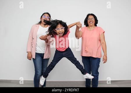 La jeune fille latine de 5 ans a le soutien de sa mère à la peau foncée et de sa grand-mère avec des lunettes pour les soins et l'éducation Banque D'Images