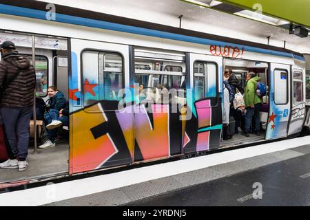 Passagers du métro de Paris, en train couvert de graffitis. Banque D'Images