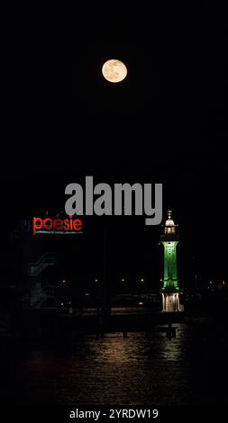 La pleine lune se lève derrière le phare des bains des Paquis à Genève Banque D'Images