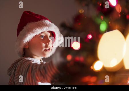 Portrait d'un garçon de 8 ans décorant l'arbre de Noël Banque D'Images