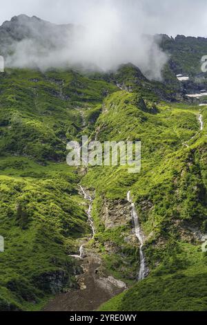 Un panorama de montagne avec une cascade, une végétation luxuriante et des nuages bas suspendus, mittersill, hohe tauern, autriche Banque D'Images