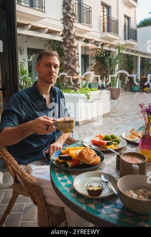 L'homme profite du petit déjeuner dans la cour de style marocain au Boutique Hotel Banque D'Images