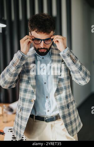 Homme d'affaires focalisé ajustant les lunettes dans un cadre de bureau moderne Banque D'Images