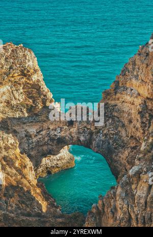 La lumière du soleil illumine de superbes formations rocheuses et des eaux turquoises à ponta da piedade à lagos, algarve, portugal, avec une arche rocheuse naturelle Banque D'Images
