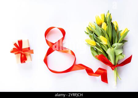 rouge numéro huit, boîte cadeau emballée et tulipes jaunes sur blanc. Contexte pour la journée des femmes, 8 mars. Style de pose à plat, vue de dessus, maquette, modèle Banque D'Images