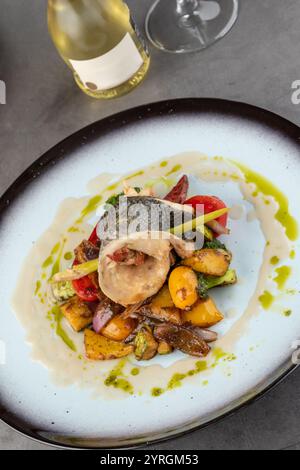 Crevettes enveloppées de bar sur divers légumes sur une assiette en porcelaine Banque D'Images