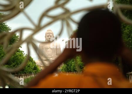 Un moine faisant attention à une statue de 64 pieds de haut du Grand Bouddha derrière la clôture à Bodh Gaya, Bihar, Inde. Banque D'Images