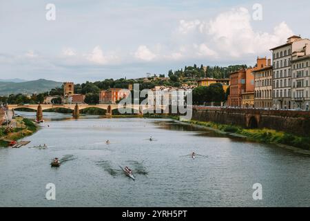 Plusieurs équipes d'aviron s'entraînent sur le fleuve arno à florence avec ponte san niccolo et des bâtiments florentins typiques en arrière-plan Banque D'Images