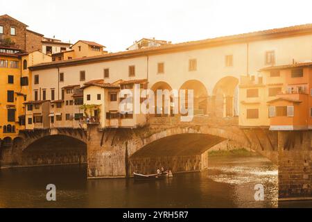 Le pont historique du ponte vecchio à florence brille au coucher du soleil, se reflétant sur le fleuve arno, créant une scène italienne pittoresque Banque D'Images
