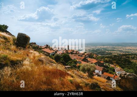 Monsanto village médiéval construit au milieu de grands rochers de granit domine le paysage environnant avec sa tour d'église et ses toits de tuiles sous un nuage Banque D'Images