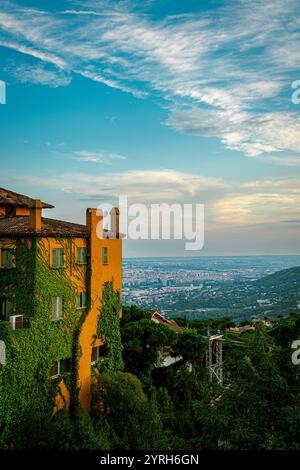 Vue panoramique de barcelone depuis le mont tibidabo au coucher du soleil avec un bâtiment coloré couvert de lierre Banque D'Images