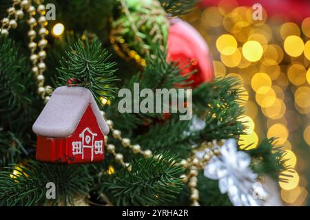 Célébration du nouvel an, branches d'arbre de Noël avec maison de jouet sur fond de lumières dorées Banque D'Images