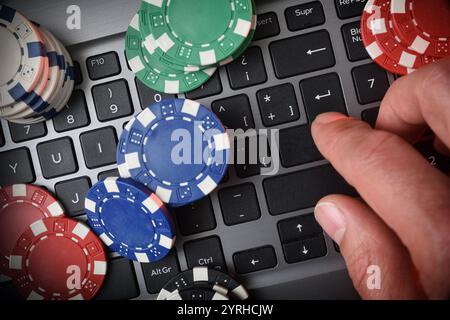 Concept de Paris de jeu en ligne avec des jetons sur le clavier d'ordinateur portable et la main appuyant sur la touche entrée. Vue de dessus. Banque D'Images