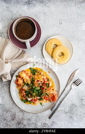 Omelette salée aux œufs de poule avec tomate et fromage, cuite dans l'huile d'olive servie avec du café noir et des biscuits pour un petit déjeuner équilibré et sain Banque D'Images