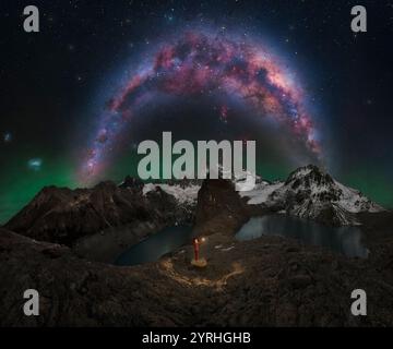Vue nocturne captivante de la voie lactée surplombant le mont Fitz Roy Une personne tenant une lanterne se dresse sur un terrain rocheux baigné de lumière céleste Banque D'Images