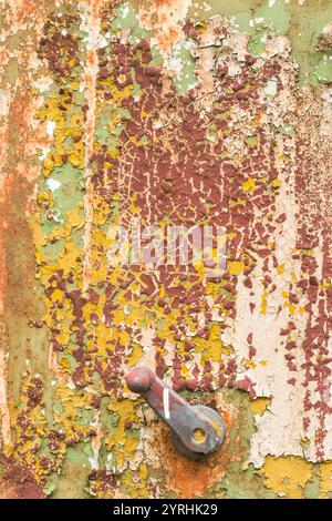 Un gros plan d'une poignée et du métal usé avec de la peinture pelable en vert, jaune et rouille couleurs la texture et l'aspect usé mettent en évidence la pourriture industrielle an Banque D'Images