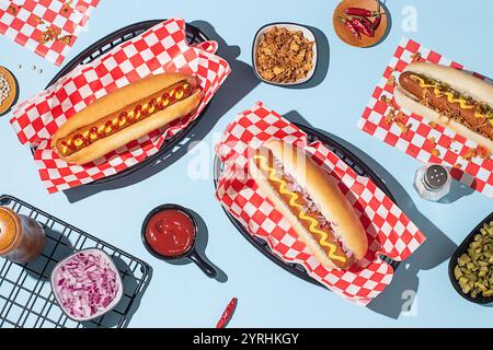 Plan suspendu de hot-dogs dans des paniers, servi avec du ketchup et de la moutarde sur un fond bleu vif Banque D'Images