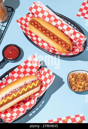 Pose à plat de hot dogs dans des paniers, servis avec ketchup et moutarde sur un fond bleu vif Banque D'Images