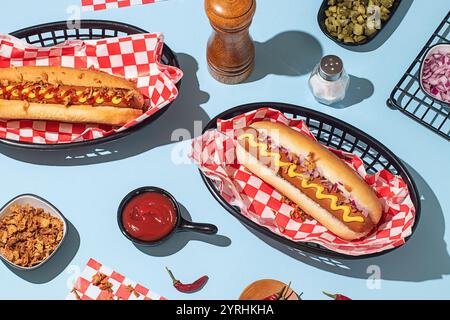 Plan suspendu de hot-dogs dans des paniers, servi avec du ketchup et de la moutarde sur un fond bleu vif Banque D'Images