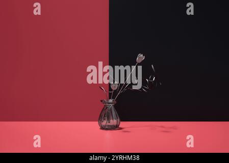 Élégant décor de fleurs décoratives séchées placées dans un vase en verre transparent sur un fond rouge et noir saisissant, parfait pour ajouter une touche de Banque D'Images