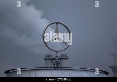 Stuttgart, Allemagne. 04th Dec, 2024. Le logo Mercedes-Benz est visible sur la succursale du constructeur automobile de Stuttgart devant les nuages d'une cheminée de la centrale de cogénération de Gaisburg. Crédit : Marijan Murat/dpa/Alamy Live News Banque D'Images