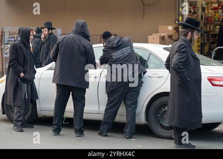 Une scène de rue à Williamsburg Brooklyn avec un volontaire des services d'urgence de Chaveirim essayant de déverrouiller une porte de voiture sans clé. Sur Lee Avenue. Banque D'Images