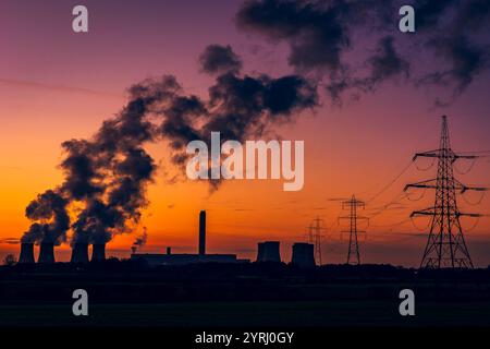 Silhouette des tours de refroidissement d'une centrale électrique contre un magnifique coucher de soleil d'hiver près de Drax dans le North Yorkshire, Royaume-Uni, avec des pylônes électriques et un panache Banque D'Images