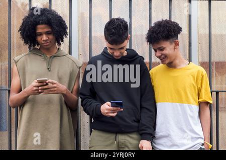Trois amis naviguant sur Internet sur leur téléphone mobile Banque D'Images
