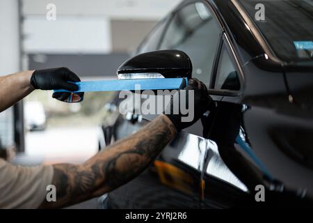 Homme professionnel sapes voiture noire avant le polissage. Habillage Banque D'Images