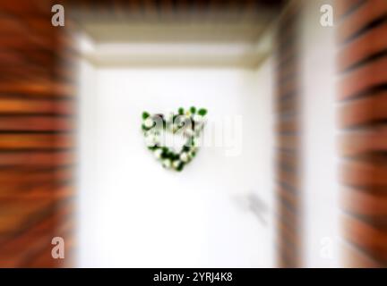 Couronne de fleurs de mariage (ou de naissance) en forme de coeur sur la porte. Londres, Royaume-Uni. Photo abstraite floue. Banque D'Images