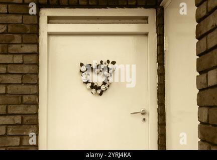 Couronne de fleurs de mariage (ou de naissance) en forme de coeur sur la porte. Londres, Royaume-Uni. Photo historique de Sépia. Banque D'Images