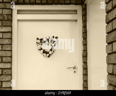 Couronne de fleurs de mariage (ou de naissance) en forme de coeur sur la porte. Londres, Royaume-Uni. Photo historique de Sépia. Banque D'Images