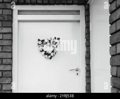 Couronne de fleurs de mariage (ou de naissance) en forme de coeur sur la porte. Londres, Royaume-Uni. Photo historique noir et blanc. Banque D'Images