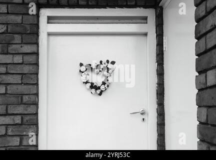 Couronne de fleurs de mariage (ou de naissance) en forme de coeur sur la porte. Londres, Royaume-Uni. Photo historique noir et blanc. Banque D'Images