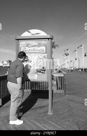 Touriste caucasien mâle lisant un panneau directionnel sur une promenade en bois à Myrtle Beach, Caroline du Sud, États-Unis. Banque D'Images