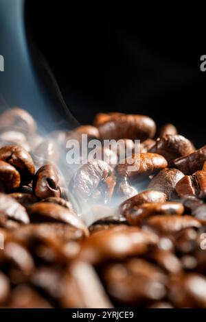 Gros plan des grains de café fumants sur fond noir Banque D'Images