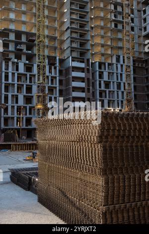 Construction en cours d'appartements modernes de grande hauteur avec grues, renforts en acier et structures inachevées. Banque D'Images