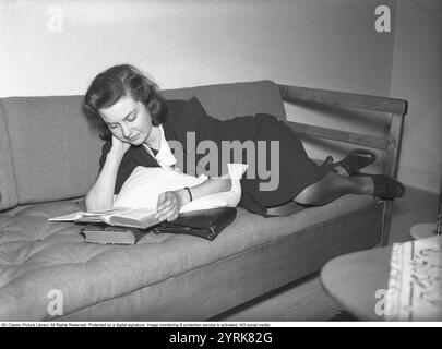 Dans les années 1940 Une jeune femme à la maison lisant un livre tout en étant couchée à l'aise sur un canapé. Février 1940 Kristoffersson ref 53-1 Banque D'Images