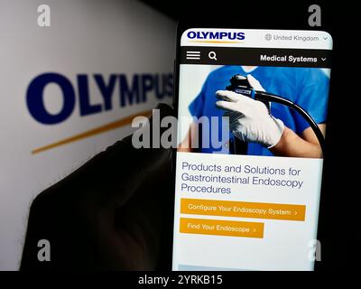 Dans cette illustration photo, une personne tient un téléphone portable avec la page Web de la société d'optique japonaise Olympus Corporation devant le logo. Banque D'Images