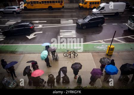 Les clients avec leurs chariots font la queue sous la pluie devant le garde-manger Holy Apostles à Chelsea à New York pour une distribution de nourriture de Thanksgiving le mardi 26 novembre 2024. (© Richard B. Levine) Banque D'Images