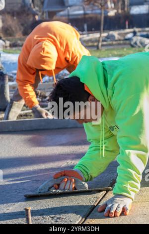 Detroit, Michigan - les ouvriers versent et finissent le béton pour les sentiers pédestres dans Three Mile Park dans le quartier Morningside de Detroit. Banque D'Images